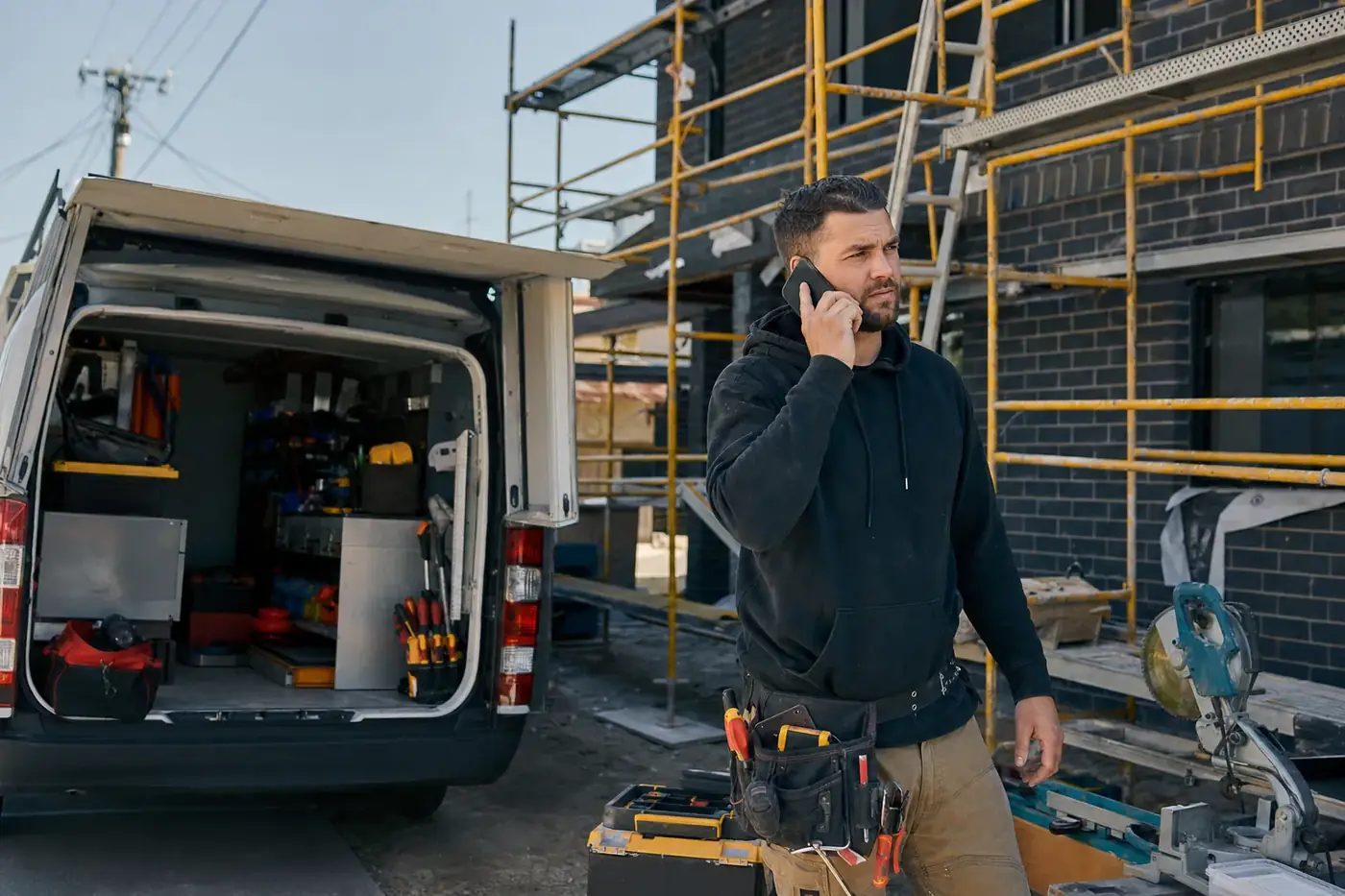 Melbourne tradesman checking job enquiries on his phone at a work site